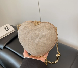 Detail of a heart-shaped crossbody bag with gold sequins and a heart-shaped metal zipper