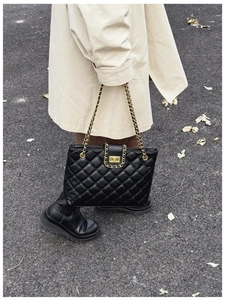 Détails de la texture en cuir noir matelassé et chaîne dorée de la bandoulière