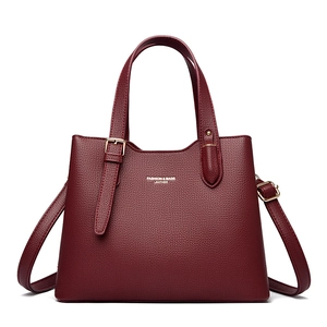 Detail of burgundy lychee pattern tote bag with gold logo and adjustable shoulder strap