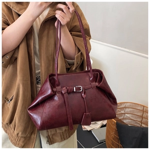Detail view of burgundy leather shoulder bag with silver buckle and knot accents