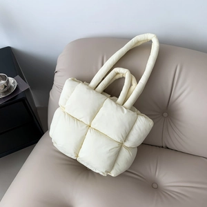 Sac fourre-tout matelassé beige chic avec poignées rembourrées sur fond de canapé