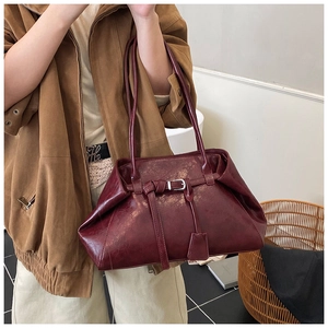 Detail of vintage burgundy tote bag showing rich leather texture and buckle element