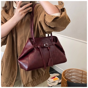 Detail of a vintage dark red leather shoulder bag worn by model in a minimalist setting