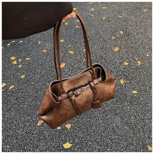 Close-up of vintage dark brown faux leather texture and decorative strap on a tote bag