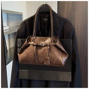 Detail of vintage brown oil-wax leather shoulder bag with decorative buckle and long strap