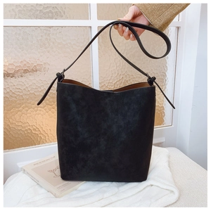 Detail of matte black bucket bag with adjustable strap and contrast brown interior lining