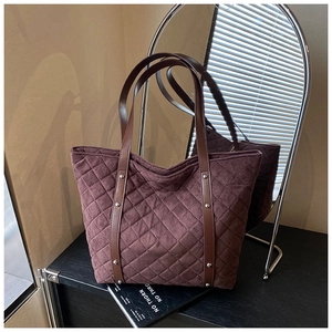 Detail of dark brown quilted tote bag with matte finish and reinforced leather handles