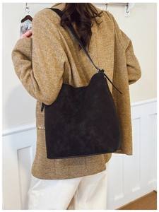 Matte black bucket bag worn by model in a professional commuting scene