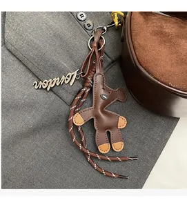 Detail of brown leather bear charm with London tag on woven strap of suede dumpling bag
