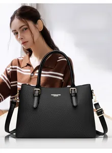 Detail of black woven texture leather tote bag with gold hardware and shoulder strap