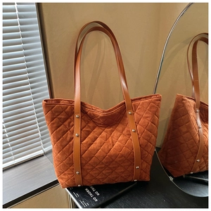 Detailed macro view of caramel quilted tote bag featuring silver studs and suede texture