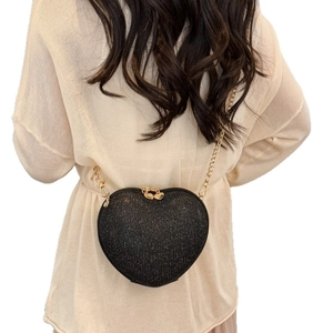 Glittery heart-shaped crossbody bag with gold chain strap shown on a model