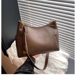 Detail view of coffee brown PU leather bag with logo embossing and gold metal buckle