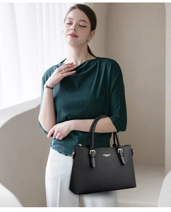 Detail of black textured leather tote with gold fashion lettering and metal buckle