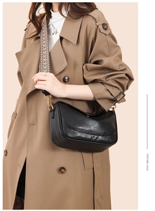 Détail du sac demi-lune en cuir noir avec bandoulière tissée et finitions dorées