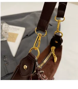Detail of durable gold metal hook and zipper on brown leather and suede shoulder bag