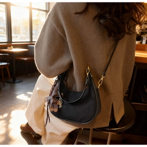 Detail of black saddle bag with bear charm and London pendant on adjustable strap