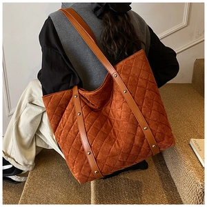 Quilted orange-brown tote bag in corduroy with silver studs shown on a model