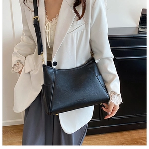 Detail of black matte leather shoulder bag with adjustable strap and golden metal buckle