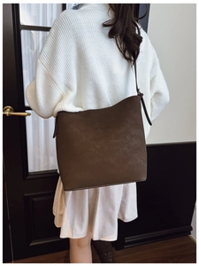 Detail of dark brown matte suede bucket bag showing texture and adjustable strap design