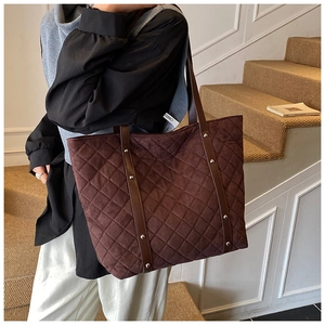 Detail of dark brown quilted tote bag with diamond stitching and silver metal rivets