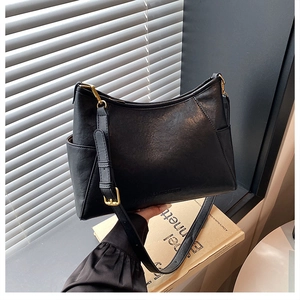 Detail of minimalist black leather crossbody bag with golden hardware and adjustable strap