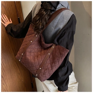 Close-up of quilted dark brown tote bag with studded leather shoulder strap detail