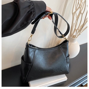 Close-up of black PU leather shoulder bag featuring golden buckles and side pockets