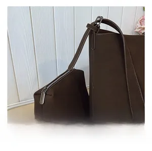 Detail view of smooth gunmetal zipper and matte dark brown bucket bag set with pouch