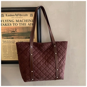 Detailed view of dark brown quilted suede tote bag with silver metal studs and leather strap