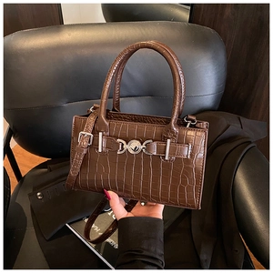 Detailed view of dark brown faux crocodile leather texture and silver buckle on handbag