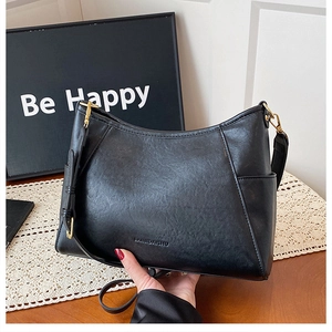 Detail of black faux leather handbag featuring brand logo and gold metal buckle accents