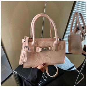 Detail view of pink crocodile embossed handbag with heart-shaped metal buckle and silver strap
