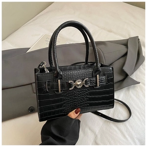 Detail of black crocodile pattern handbag with heart metal buckle and crossbody strap