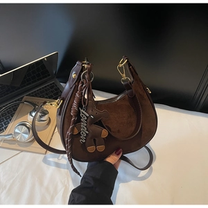 Detail of dark brown suede hobo bag with leather trim and decorative bear charm