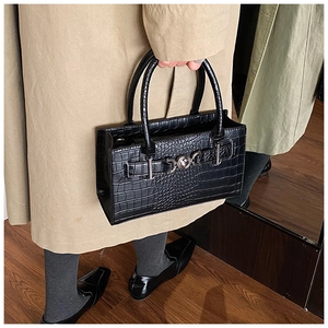 Close-up of black crocodile pattern leather texture with silver buckle on the stylish handbag