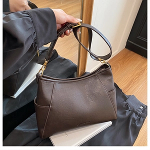 Detail view of dark brown leather shoulder bag featuring side pocket and gold hardware