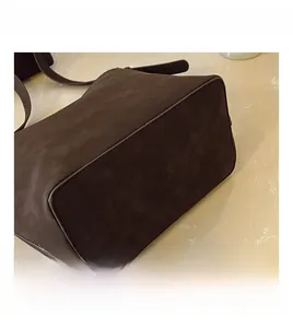 Detail view of the stitching and frosted texture on a dark brown bucket bag