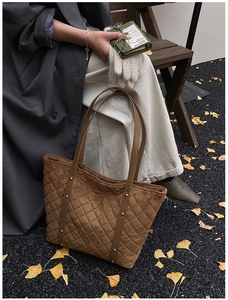 Close-up of brown quilted tote bag in suede finish with long shoulder straps for autumn