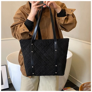 Detail of black quilted tote bag with silver studs and elegant diamond stitching texture