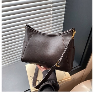 Detail of dark brown tote bag featuring litchi texture leather and gold metal buckles