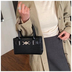 Detail of crocodile pattern leather and golden heart lock on a black handbag
