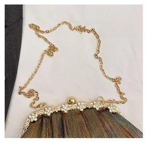 Close-up of evening bag with metallic fabric and gold floral rhinestone clasp detail