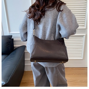 Detail of dark brown leather tote bag with metal base studs and adjustable shoulder strap