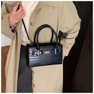 Crocodile pattern leather handbag worn by a model in a warm indoor setting