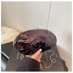 Detail of a dark purple shell-shaped evening clutch with gold metal frame and chain