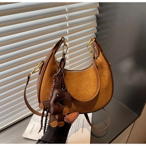 Close-up of vintage brown suede half-moon bag with gold zippers and a bear charm
