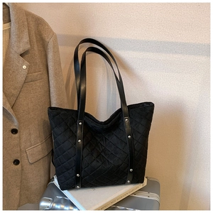 Close-up of black quilted tote bag with silver studs and diamond lattice texture