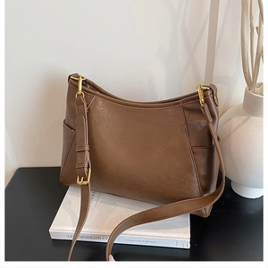 Close-up of vintage brown PU leather bag with gold hardware and side pocket on books