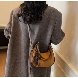 Detail of vintage suede hobo bag with leather trim and London tag on grey wool coat